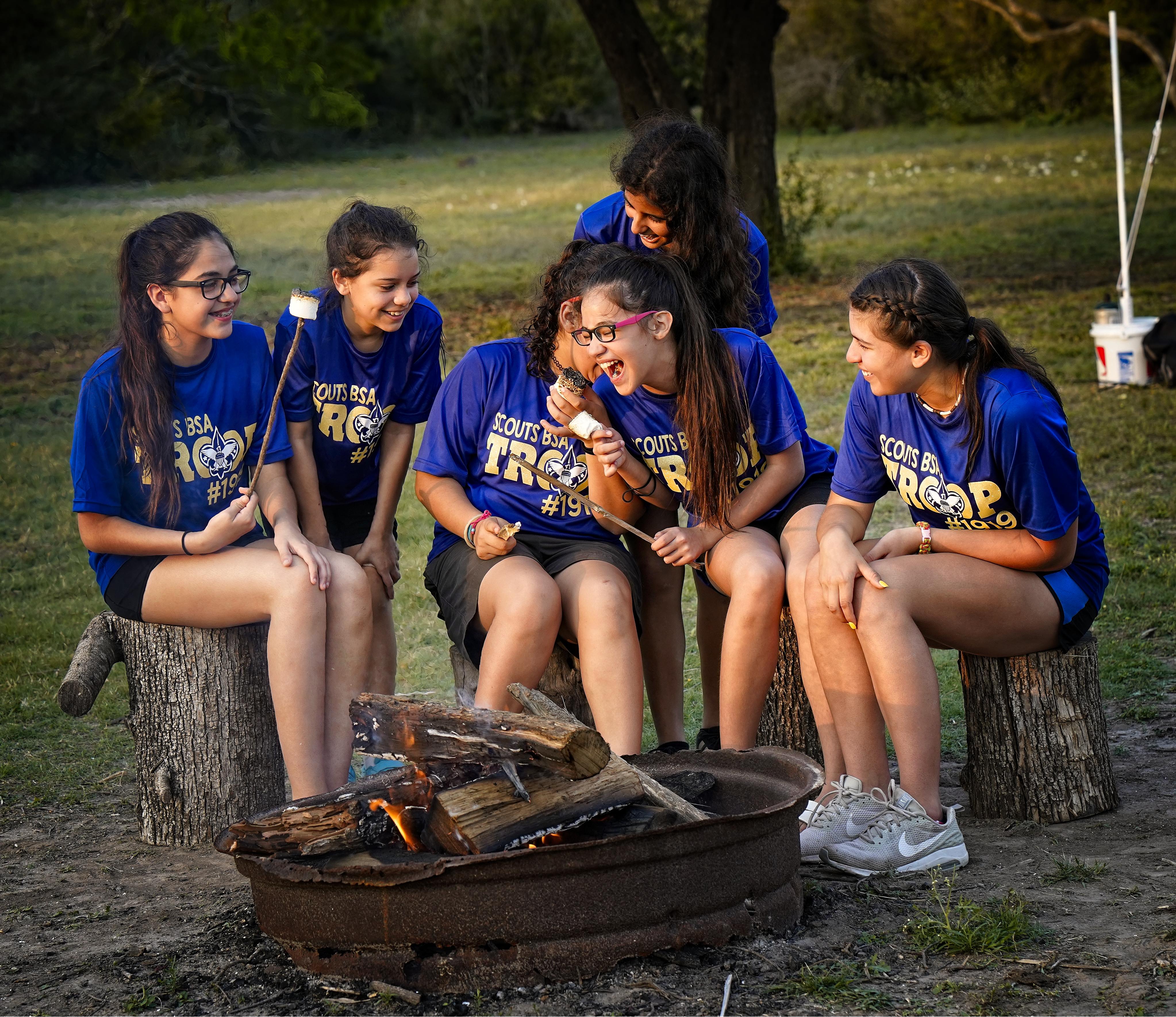 Girls in Scouting havingfun around a campfire